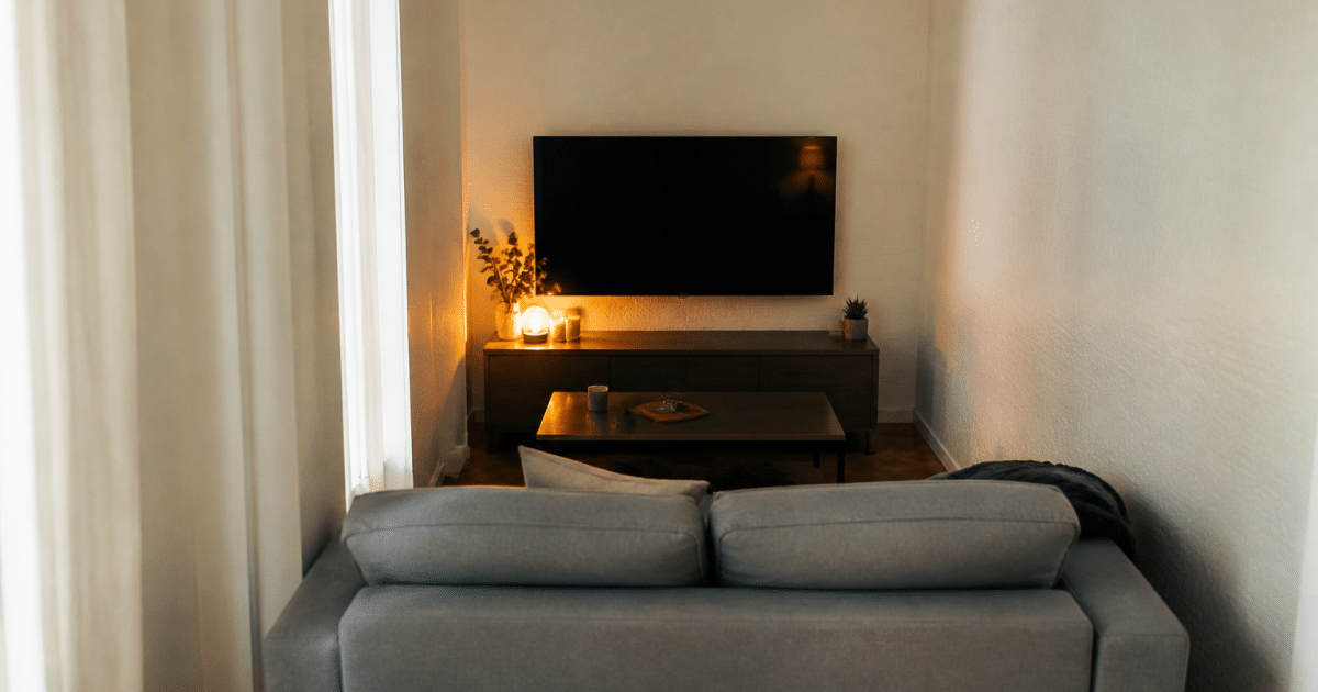 Canape gris face a television murale dans piece etroite