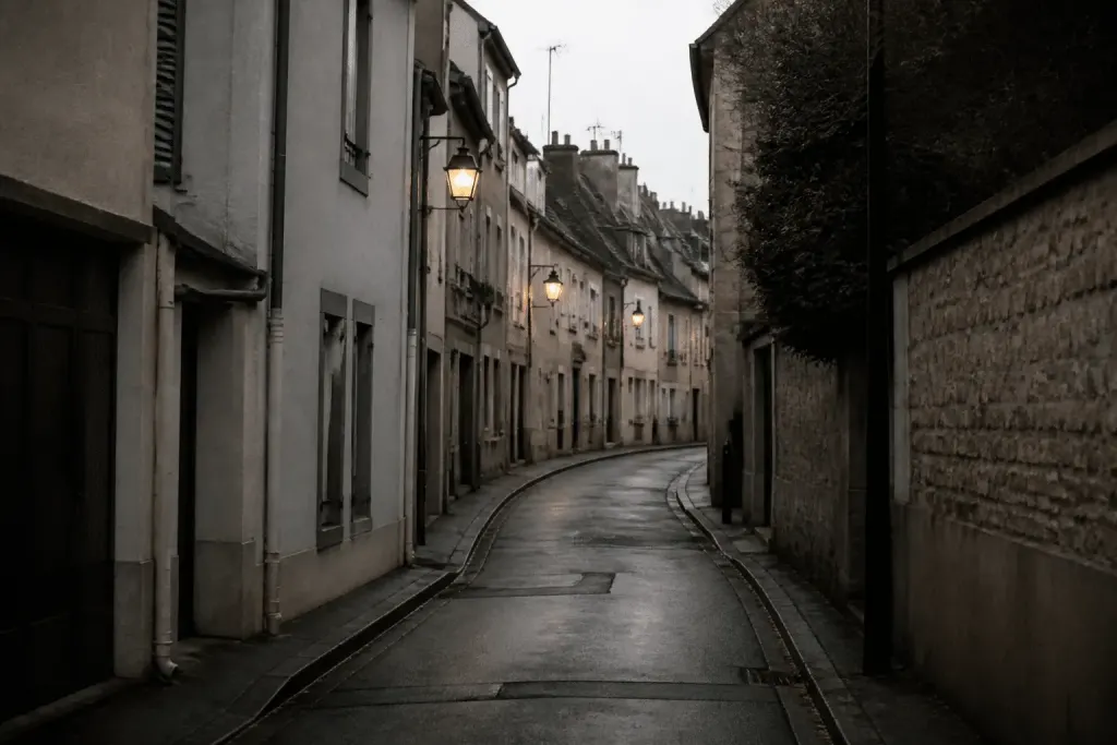 Rue sombre de Mont-Mesly avec facades grises et lanternes allumees