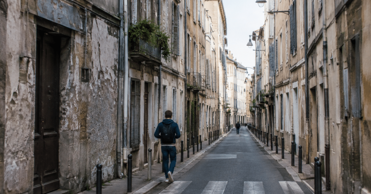 Rue urbaine étroite avec immeubles dégradés surplombant passage piéton