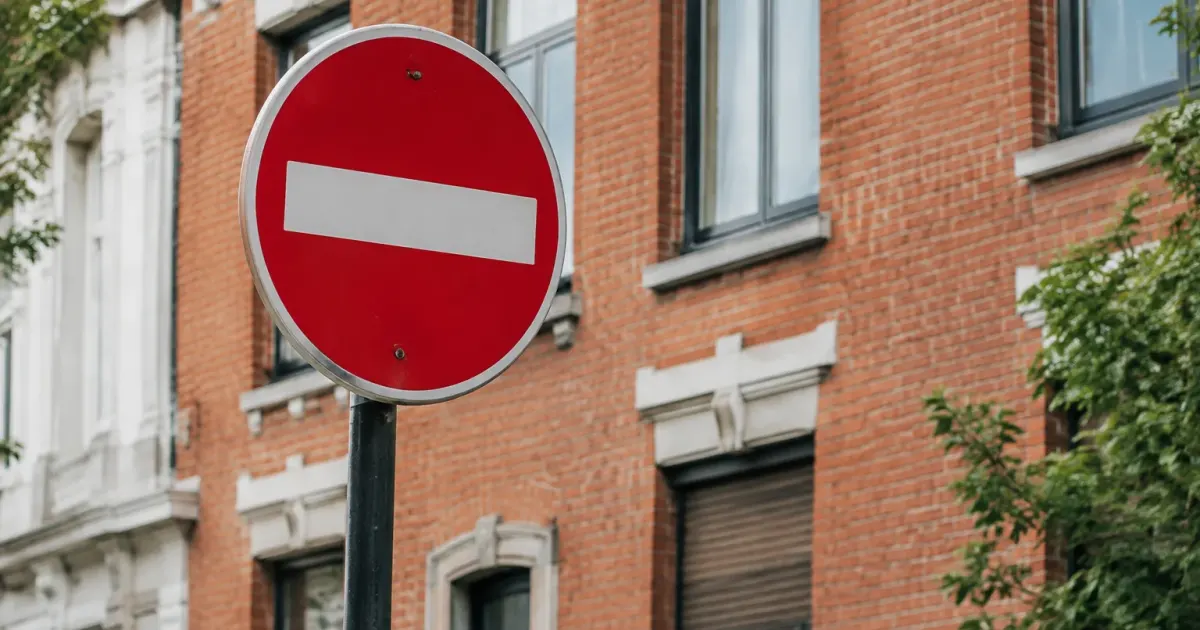 Panneau de signalisation rouge devant un immeuble de briques