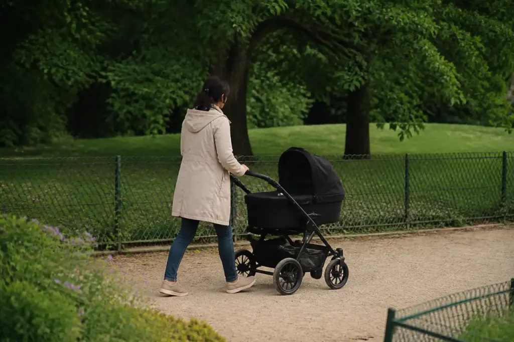 Parent poussant une poussette devant un parc verdoyant